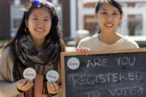 Two women holding signage to promote voting