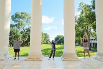 Students with hands spelling out UVA under columns at the Rotunda
